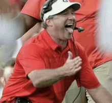 a man wearing a red shirt and white hat with the letter g on it