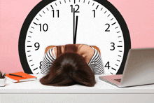 a woman rests her head on a desk in front of a clock that shows the time as almost 5:00