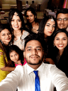 a group of people posing for a selfie including a man in a blue tie