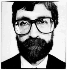 a man with glasses and a beard is wearing a suit