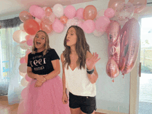 two women are standing in front of balloons and one has a shirt that says optimise