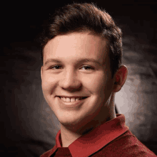 a young man wearing a red shirt is smiling