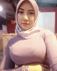 a woman wearing a purple sweater and a hijab holds her hands on her hips