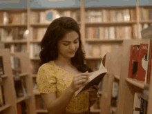 a woman in a yellow dress is reading a book in front of a shelf with a book titled " a few lines "