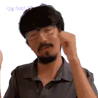a man with glasses and a beard is scratching his ear