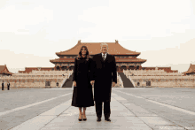 a man and a woman are standing in front of a chinese building