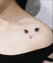 a woman has a small tattoo of a cat 's face on her shoulder