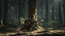 a woman sits under a tree playing a guitar in the woods