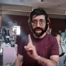 a man with glasses and a beard is pointing his finger up