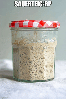 a jar of sauerteig-rp sits on a white cloth