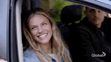 a woman is sitting in the back seat of a car smiling .