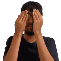 a man covering his face with his hands and wearing glasses