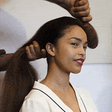 a woman is getting her hair done by a man