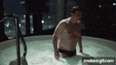 a man in a bathing suit is standing in a jacuzzi with a make a gif.com watermark