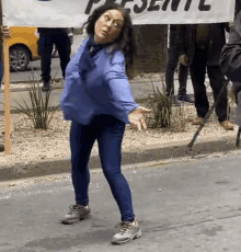 a woman in a blue shirt is holding a banner that says presente