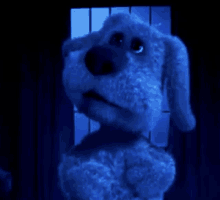 a blue stuffed dog is standing in front of a window looking out .