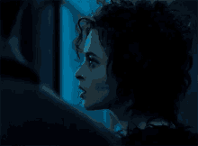 a close up of a woman 's face in a dark room with a blue background .