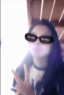 a woman wearing sunglasses that say 50 % angel 50 % demon giving a peace sign