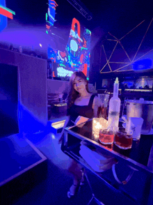 a woman sits in a dark room with a tray of drinks on a table