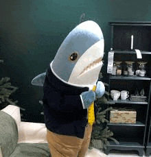 a stuffed shark mascot is standing next to a couch in a living room .