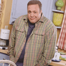 a man in a plaid shirt is standing in a kitchen