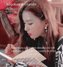 a woman is writing in a notebook with the words kugokan anotando on the bottom