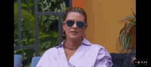 the woman is wearing sunglasses and a purple shirt .