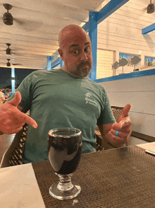 a man sitting at a table with a glass of wine and a t-shirt that says ' emerald isle '