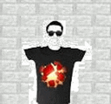 a man wearing sunglasses and a black t-shirt with a fireball on it is standing in front of a wall .