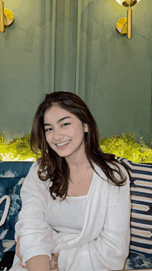 a woman in a white sweater sits on a blue and white couch