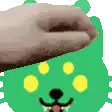 a person 's hand is reaching out towards a green bear 's face .
