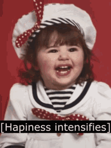 a little girl is wearing a hat and smiling with the words happiness intensifies behind her .