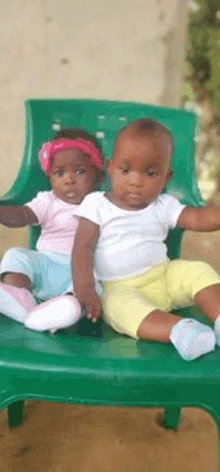 a boy and a girl are sitting on a green plastic chair