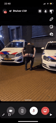 a phone screen shows a man taking off his shirt in front of two police cars