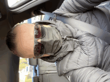 a man wearing sunglasses and a face mask is sitting in a car