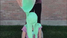 a woman pours green slime on a girl 's face