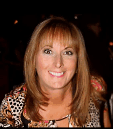 a woman wearing a leopard print shirt is smiling for the camera