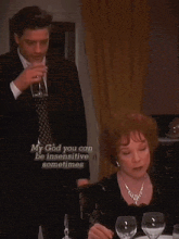a man in a suit and tie stands next to a woman at a table with a caption that says my god