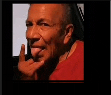 a man in a red shirt is sticking his tongue out while making a funny face .