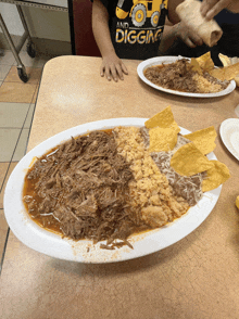 a child wearing a shirt that says " and digging " is eating a meal