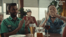 a man and a woman sitting at a table applauding with the words " you 're my hero " above them