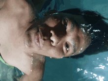 a shirtless man is swimming in a pool and his face is partially visible