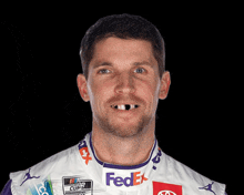 a man with a missing tooth is wearing a fedex jersey