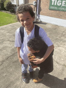 two young boys are hugging in front of a sign that says tiger respectful responsive