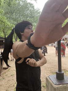 a man wearing a black shirt with a dragon wing on his shoulder