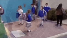 a group of children are standing on a sidewalk in front of a building .