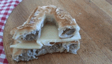 a piece of bread with cheese on top of it on a wooden cutting board .