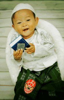 a baby with a spiderman embroidered on his shorts holds a book