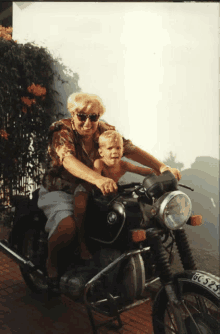 a woman is sitting on a motorcycle with a child on her lap