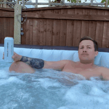 a man in a hot tub holding a stella artois can